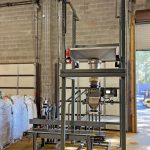 bulk bag unloading system repackages water filter media into open mouth bags