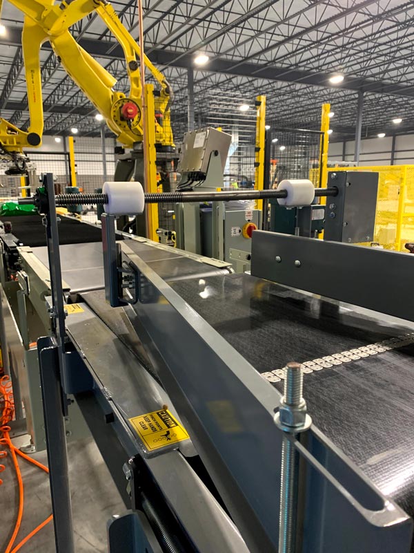 pacing conveyor to bag palletizing robot - jack screw can be adjusted to center bag on conveyor