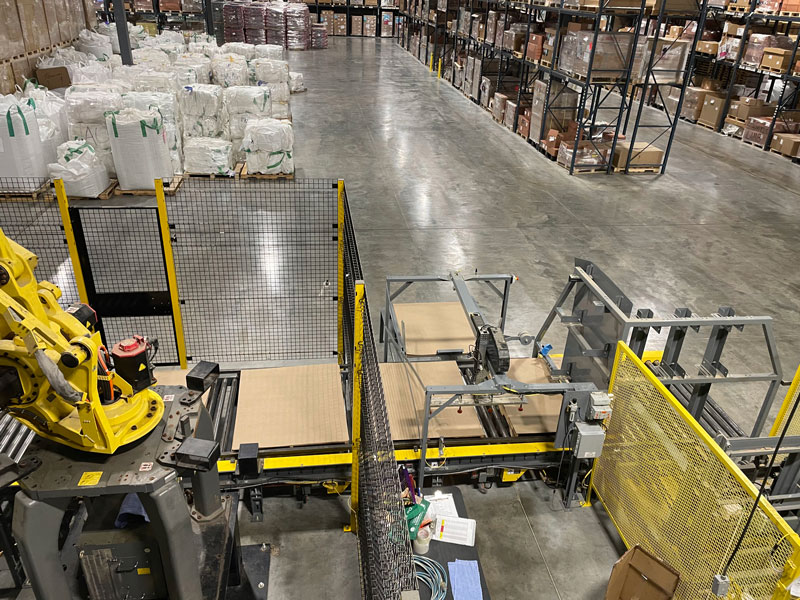 Pallet dispenser with safety fencing and slip sheet dispenser in robotic palletizing system