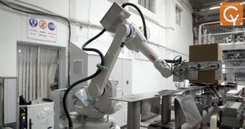 Robotic arm sliding empty box on rail to close flaps and apply tape