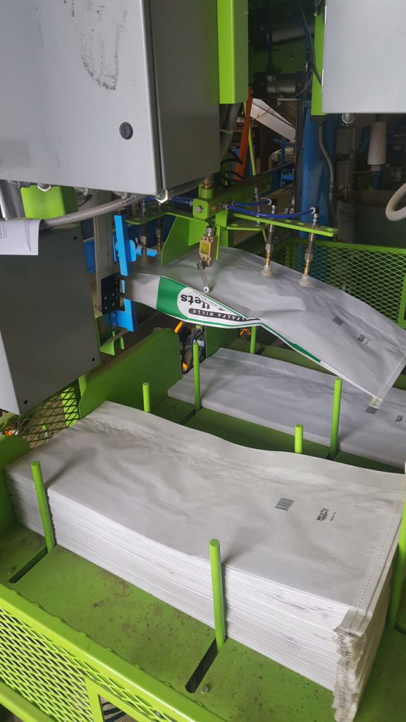 view of bag placer picking up empty open mouth paper bag