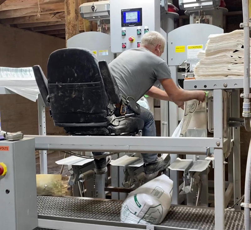 bags of fertilizer on discharge conveyor under operators chair valve bag fillers