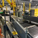pacing conveyor to bag palletizing robot - jack screw can be adjusted to center bags on conveyor