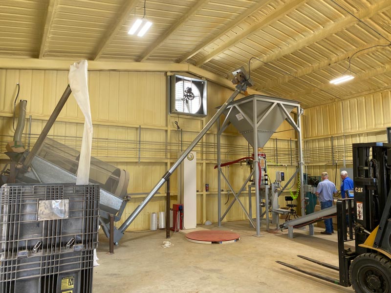 auger conveyor lifts corn into surge hopper above bagging machine