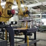 bag palletizing robot picks up bags of animal feed off of pick conveyor