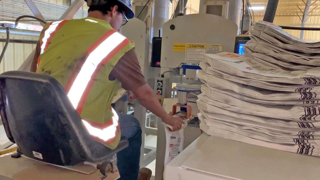 Operator placing valve bags on valve bag filling machines