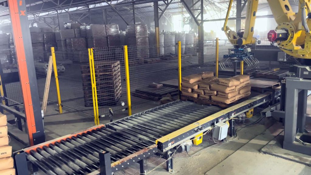 bag palletizing robot stacking 50 lb bags on right bagging line