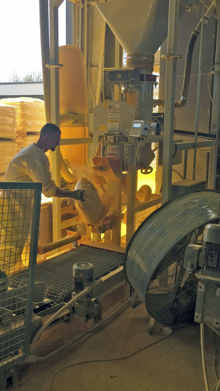 50 lb inclusion bag of paint pigment powder tipping onto discharge conveyor