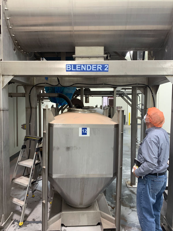 Blended seasoning mix being loaded into stainless steel IBC
